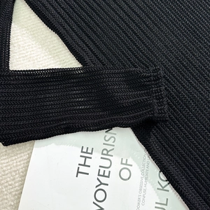 Detailed macro view of black herringbone knit texture on a three-piece bikini swimsuit