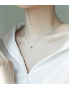 Dettaglio di una collana in argento s925 con ciondolo a gemma blu tonda su modella
