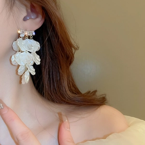 Détail macro de grandes boucles d'oreilles à pétales blancs et cristaux de zircon