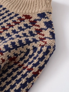 Close-up of houndstooth knit fabric texture in navy red and beige with ribbed hem detail