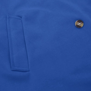 Detailed close-up of blue coat pocket featuring high-quality fabric and dark brown button