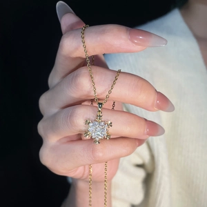 Detailed view of a gold snowflake pendant necklace set with sparkling white zircon crystals