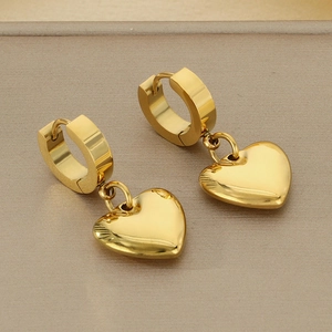 Close-up of golden hollow heart pendant earrings with a high-polished mirror finish