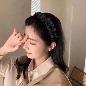 Close-up of a pleated black fabric headband worn by a model for an elegant daily look