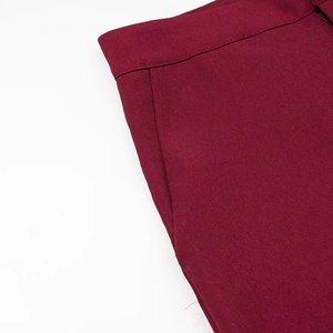 Close-up of wine red slim-fit trousers showing twill fabric texture and pocket seams