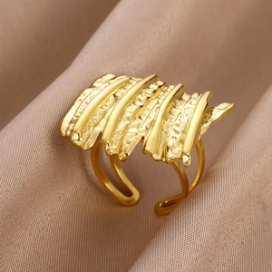 Macro shot of gold wide chunky ring with rippled texture on champagne silk fabric