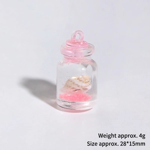 Gros plan d'une bouteille miniature avec un petit coquillage et du sable rose dedans
