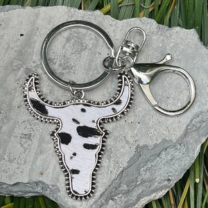 Western style bull head keychain with cow print texture on a natural stone background