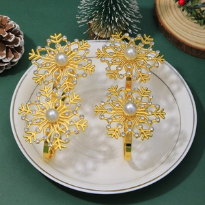 Detail of four golden snowflake napkin rings with pearls and rhinestones on a white plate