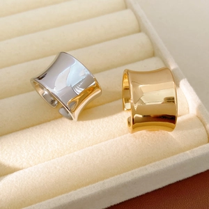 Close-up of wide concave open rings in gold and silver finish on velvet tray