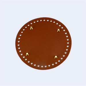 Detailed top view of a 15cm round brown leather bag base with four gold metal feet studs