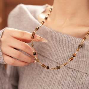 Macro view of geometric tiger eye style beaded necklace with golden spacer beads
