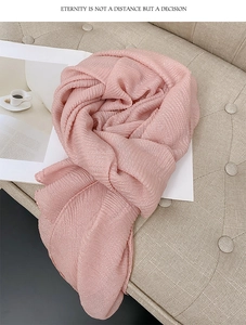 Dettaglio della sciarpa rosa plissettata con trama lucida su un morbido fondo beige
