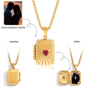Detailed view of golden tarot locket necklace with red heart stone and photo compartment
