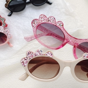 Detailed view of colorful glitter cartoon floral sunglasses for kids on a textured background