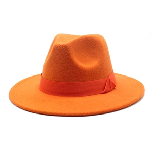 Detail of classic orange wool fedora hat with matching satin ribbon bow on white background