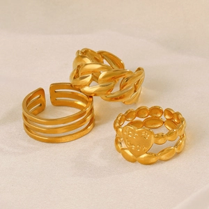 Three gold stainless steel rings with heart plaque and chain link design on white fabric