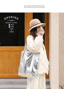 Silver metallic nylon tote bag with crinkled texture shown in a casual lifestyle street shot