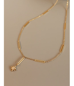 Detail of 18K gold starburst pendant necklace with unique link chain and gemstone center