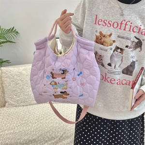 Detail of light purple quilted tote bag featuring cute dog embroidery and woven handles