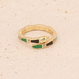 Macro detail of gold snake ring with green and black enamel and zircon accents
