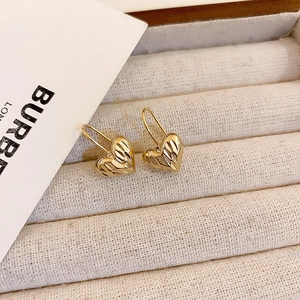 Eleganti orecchini a cuore dorati con texture a coste su vassoio in velluto beige