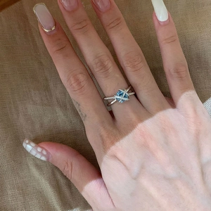 Elegant silver crisscross ring featuring a light blue square cubic zirconia stone