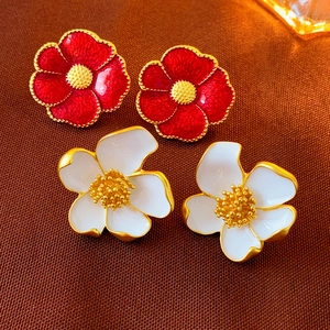 Detailed close-up of vintage flower earrings in red and white enamel with gold edges