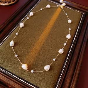 Macro view of gold-plated chain featuring irregular baroque pearls on green velvet