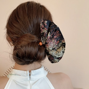 Detail of embroidered floral bow hairpin on model wearing a white traditional cheongsam