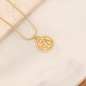 Makroaufnahme des goldenen Waage-Anhängers an einer Schlangenkette mit Gravur-Details