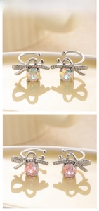 Macro detail of silver bow ear clips featuring pink and iridescent faceted crystals