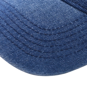 Detailed view of blue washed denim fabric and reinforced stitching on baseball cap brim