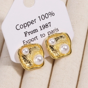Macro shot of 18k gold plated earrings with pearls on a textured jewelry card display