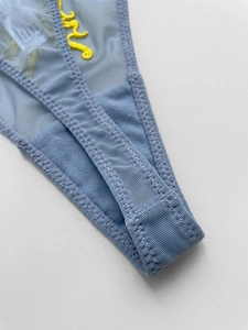 Macro detail of breathable light blue mesh fabric with intricate yellow embroidery