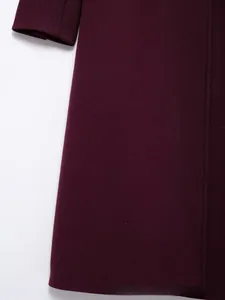Gros plan du manteau en laine bordeaux montrant la texture sergée et les coutures