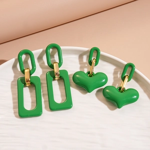Green acrylic rectangular and heart-shaped earrings on white ceramic tray