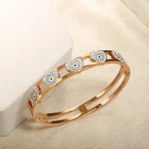 Detail of gold evil eye heart bracelet on marble and silk fabric showcase
