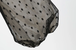 Detail of sheer black polka dot mesh fabric with velvet flocked dots and soft drapes
