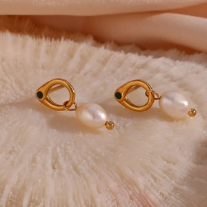 Macro detail of gold hoop earrings featuring a freshwater pearl and green gemstone accent
