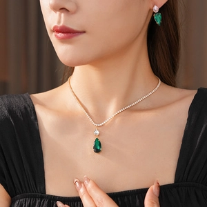 Close-up of model wearing gold water-drop green zircon necklace and matching earrings