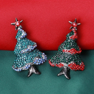 Close-up of alloy Christmas tree brooches with colorful rhinestones on festive background