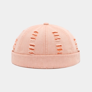 Detail view of pink docker hat featuring distressed ripped holes and orange lining
