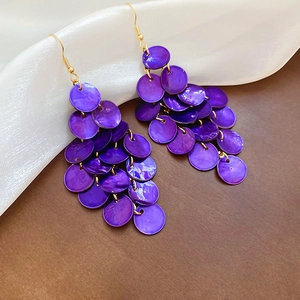 Detail of purple shell disc tassel earrings with gold hooks on white silk fabric