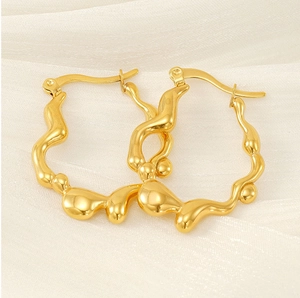 Détail de créoles irrégulières en or 18K avec une texture de métal liquide poli