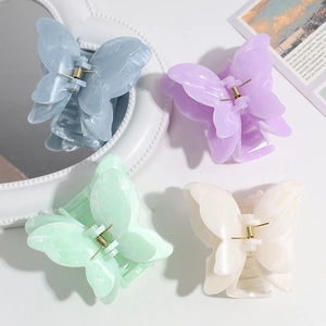 Detail of four butterfly hair claws in pastel marble colors with secure gold metal springs