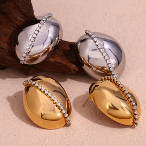 Detailed view of large oval earrings with inlaid white crystals in gold and silver finish