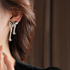 Close-up of liquid metal heart stud earring with polished silver finish on ear
