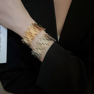 Detail of wide open cuff bracelets in polished gold and silver on a model wrist