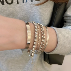 Détail d'un ensemble de cinq bracelets argentés avec chaînes gourmette, serpent et tennis